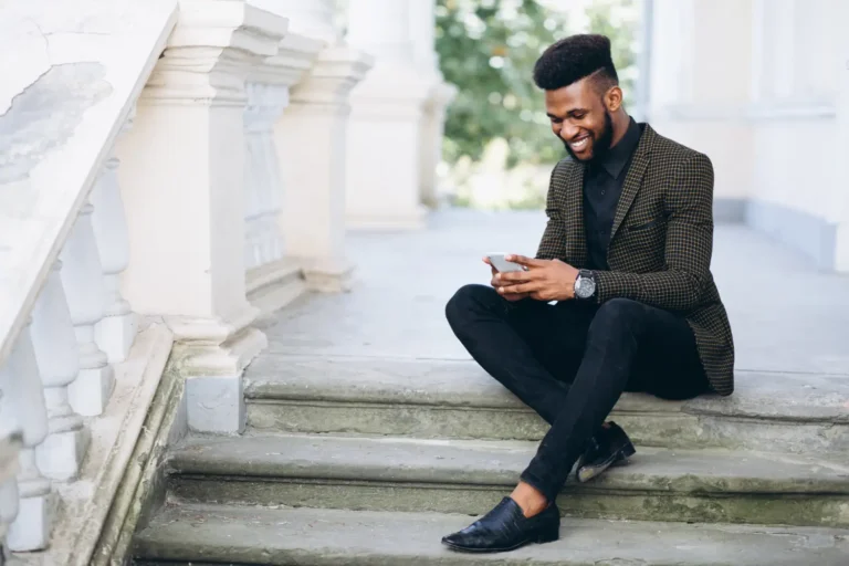 a man sitting on stairs looking at his phone-Men's Health Coaching & Fitness Training