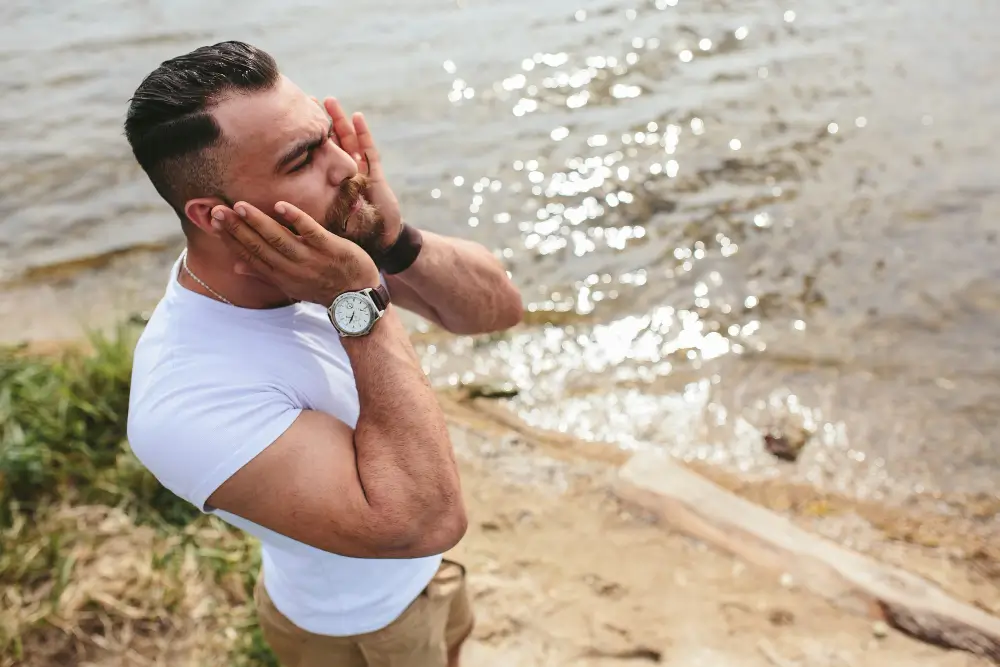 Fit and stylish man grooming by the water, embodying confidence, self-care, and the essence of summer scents -Men's Health Coaching & Fitness Trainingfor men.